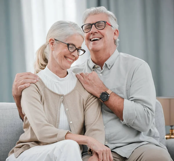 Laughing, love or funny old couple hugging on house living room sofa together enjoying quality time. Smile, peace or happy mature man bonding with a supportive senior woman in retirement at home.