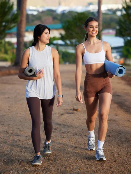 stock image Women, walking outdoor and yoga friends in nature for exercise, fitness and wellness. Young people talking in forest about workout, training and motivation for mental health, chakra and zen energy.