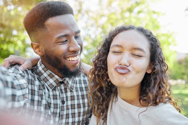 夏休みのための公園での自撮りでの友人のカップル 幸せな日付とソーシャルメディアのための面白い顔 多様性や異人種間のGen Zまたはプロフィール画像の更新と絵文字のキスを持つ自然界の若者 — ストック写真
