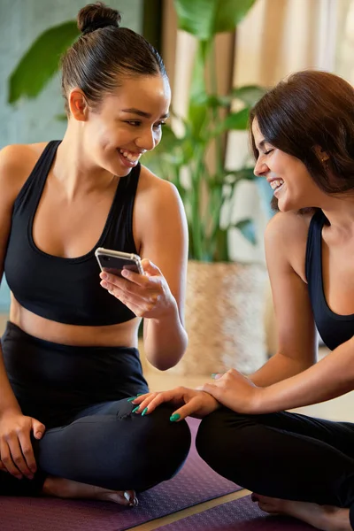朋友和瑜伽 带着手机笑社交媒体 在垫子上放松时开玩笑或迷因 快乐健康的瑜伽女人们在精神健康的情况下 在智能手机上发笑是为了好玩 — 图库照片