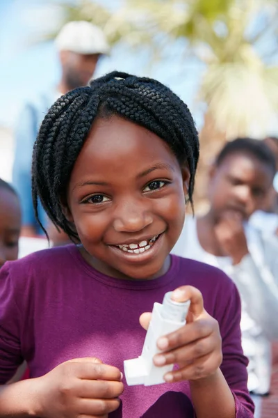Portrait of a little girl holding an asthma inhaler at a community outreach event.