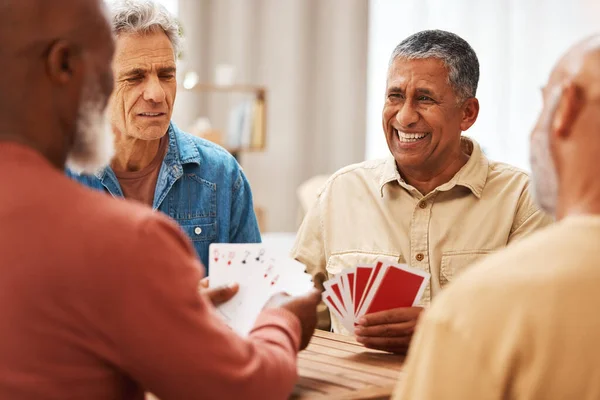Senior man, friends and playing card games on wooden table in fun activity, social bonding or gathering. Group of elderly men having fun with cards for poker game enjoying play time together at home.