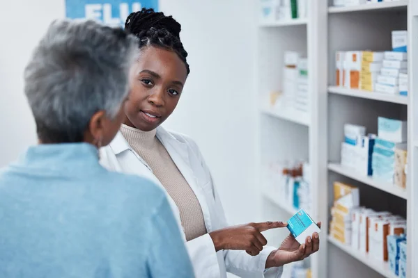 Pharmacy, black woman pharmacist and elderly patient with medication discussion of side effect. Medical clinic, doctor and pharmaceutical drugs with a healthcare, wellness and health employee at work.