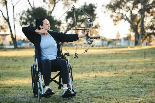 Outdoor archery, disabled woman in wheelchair and challenge for active sports lifestyle in Canada. Person with disability in a park, fitness activity to exercise arms with bow and arrow for hobby.