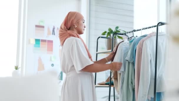 イスラム教徒の女性は ファッションデザイナーや品質保証や製品設計のために店内の衣料品のラインをチェックします ヒジャーブのイスラム女性の中小企業経営者は 鉄道や在庫の服を検査 — ストック動画