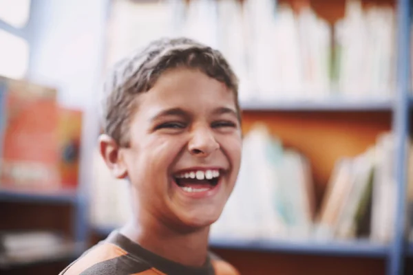 他控制不住自己的兴奋 一个兴奋的小男孩坐在图书馆里开心地笑着 — 图库照片