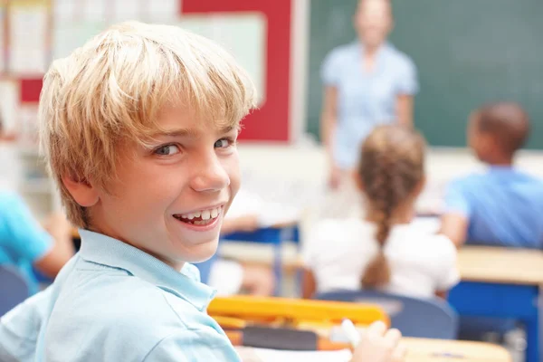 他爱学校一个可爱的金发男孩坐在课桌前的画像 — 图库照片