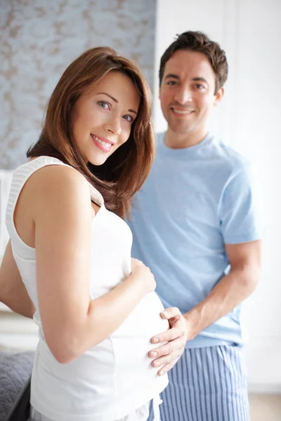 Nearly time for new beginnings. Happy young pregnant woman standing with her husband at home