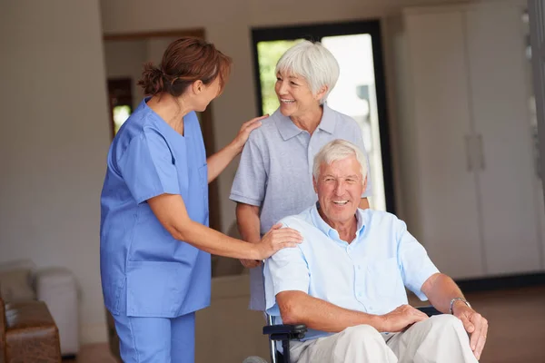 他很快就会站起来的 给她的老年病人和他的妻子带来好消息的护士 — 图库照片