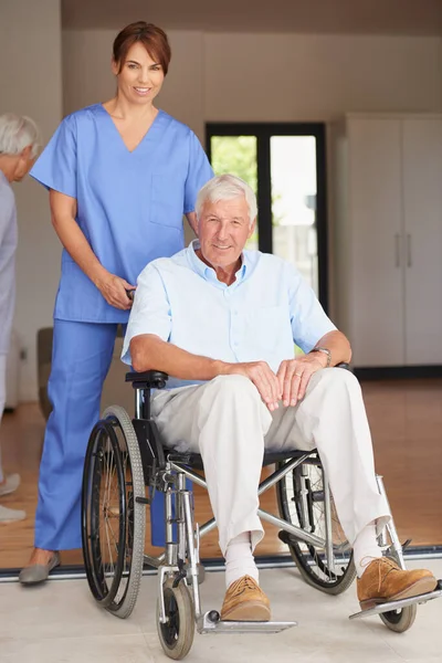 尽可能得到最好的医疗照顾 与坐着轮椅的老年病人站在一起的女医生 — 图库照片