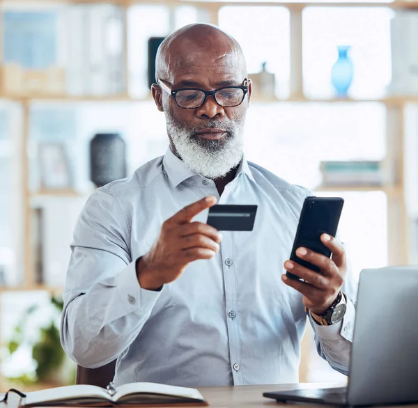 stock image Black man, credit card or phone for finance management, insurance policy or investment payment in corporate office. Serious, mature or CEO businessman on bank app, mobile technology or online fintech.