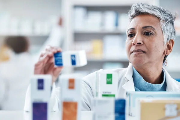 Elderly woman, pharmacist and check with box, medicine or pills by shelf in store for healthcare services. Senior pharma expert, retail stock and medical product for mockup space, health and wellness.