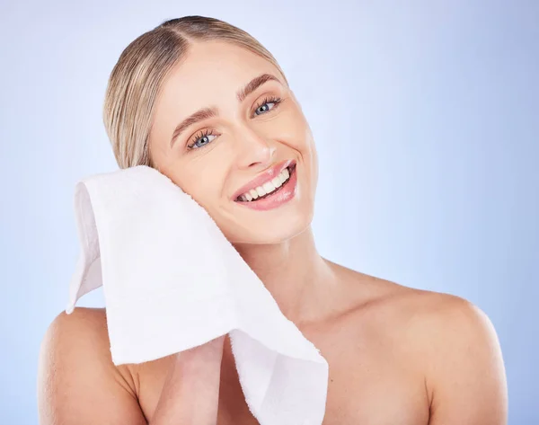 Beauty, face and woman with towel to wipe in studio isolated on a blue background. Portrait, makeup cosmetics and skincare of happy female model with fabric cloth for facial wiping for healthy skin