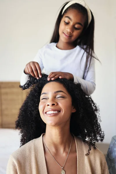 Children, black family and hair with a girl styling her mother in their home for haircare or bonding. Kids, love or style with a female child and woman bonding together over a hairstyle treatment.
