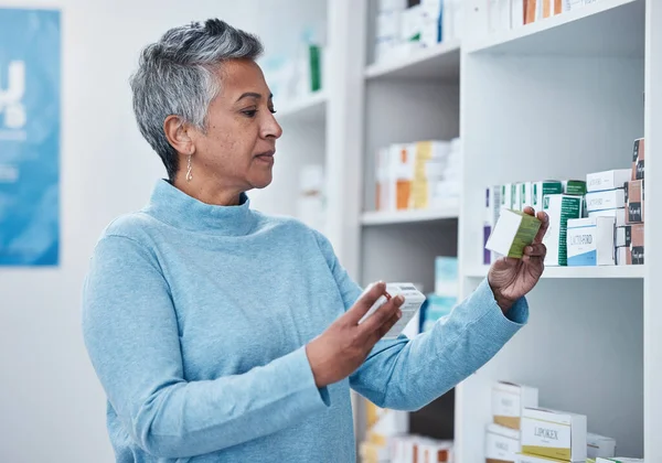 Senior woman, pharmacy and choice with box, medicine and decision with shopping for healthcare. Elderly customer, retail drugs and pharmaceutical pills for health, wellness and medical store by shelf.