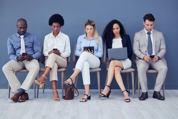 HR, technology and business people waiting in line for an interview during the recruitment process. Resume, diversity or hiring with a man and woman employee group sitting in a human resources row.