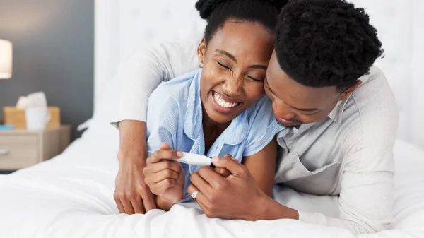 African couple, pregnancy test and planning for baby together in home, talking about happy news on bed and conversation about child in bedroom. Start of family for man and woman in marriage at house.