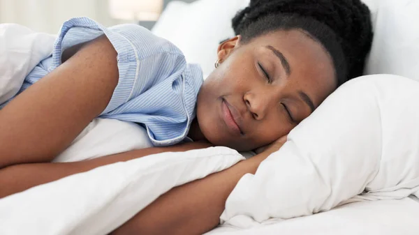 Sleep, bed and relax with a black woman sleeping in the bedroom of her home and dreaming. Resting, relaxing and peace with a young female lying on a pillow and under a duvet in a house in the morning.