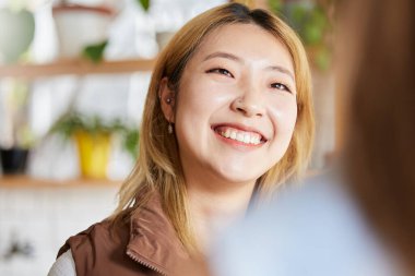 Yüz, mutlu ya da gülümse ve Asyalı bir kadın bir kafede arkadaşlarıyla vakit geçirmekten zevk alıyor. Cafe, branç ve hayat tarzı. Çekici bir genç kızla restoranda oturup sohbet etmek ya da sohbet etmek..