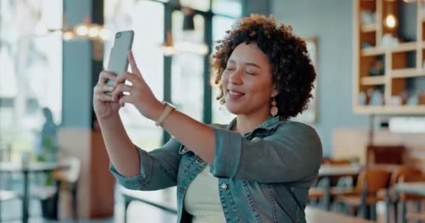 黑人女性 在室内咖啡店或零售店为自拍 博客或个人资料照片而打电话和微笑 快乐的非洲裔美国女性在智能手机上微笑着 因为她们的照片显示出和平的标志 并在亲吻 — 图库视频影像