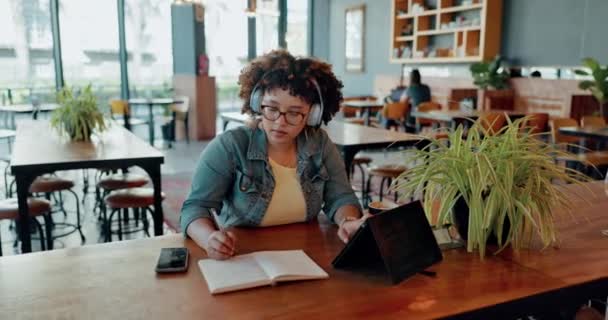 遠隔作業やコミュニケーションのためのコーヒーショップで黒人女性とタブレット ビデオ通話や書き込み カフェで働く若い女性フリーランス社員とのバーチャルミーティング ノートブック — ストック動画