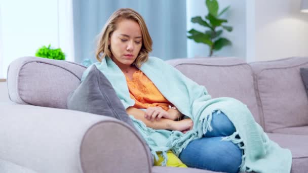 思考着 厌倦了一个亚洲女人在家里 一个人坐在客厅的沙发上 与裹在毛毯里的女性在一起的精神健康 焦虑和孤独 — 图库视频影像