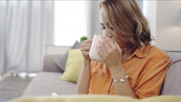 Žena Přemýšlí Doma Pije Kávu Úsměvem Pohovce Obývacím Pokoji Relaxovat — Stock video