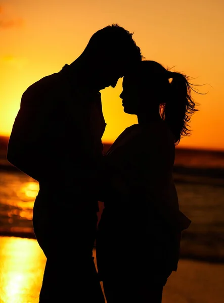 夕暮れ時のビーチでの若いカップルのシルエットは愛情を込めてお互いを受け入れます 海による新婚旅行の人々 親密な愛とロマンチックな男と女が海によって一緒に — ストック写真