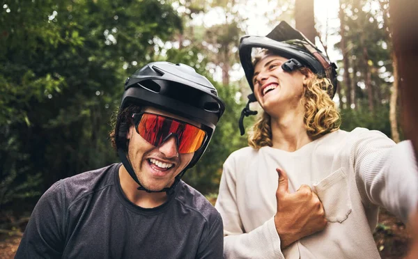 Friends, cycling men and selfie in forest, park or woods cyclist trail in nature. Thumbs up, fitness and cyclists, bikers or bike rider smile in mountain biking helmets in park outdoor bicycle ride