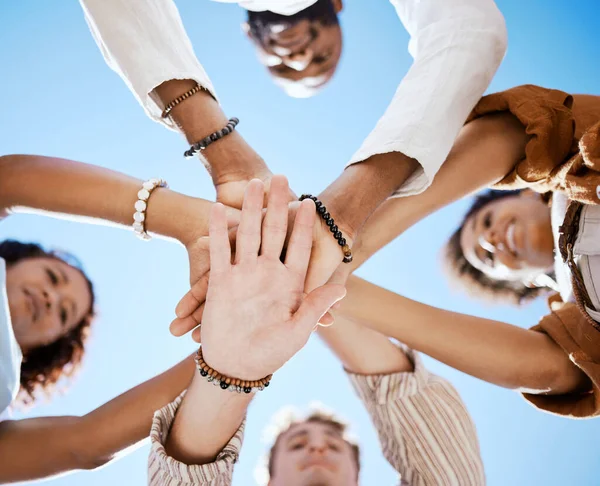 Friends, trust and support hands low angle for solidarity in multicultural group with blue sky. Care, respect and love in friendship with young people who enjoy happy emotional bond together