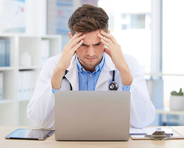 Stress, anxiety or burnout for doctor with laptop working on medicine, medical or healthcare research. Headache, head pain or migraine for hospital employee, worker or career man with digital tech.