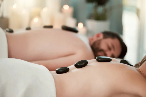 Hot stone, relax and couple with massage at spa for wellness, relax and skin therapy on holiday at a hotel. Man and woman sleeping during luxury natural cosmetics for skin and body health on vacation.