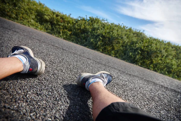 Next time I should train before I run a marathon. an exhausted runners legs as he sits next to the road