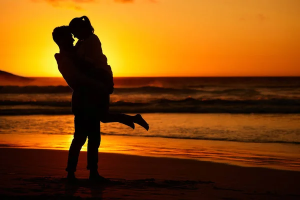 カップル ビーチ 男と女が背後に金色の景色で海岸に抱きついています 旅行のために海によって砂の上に抱擁男性と女性と愛 シルエットと海 — ストック写真