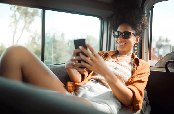 Black woman, phone and road trip in van vacation, holiday or summer trip. Relax, travel and female from Brazil on 5g mobile, social media or text message while spending quality time alone in car