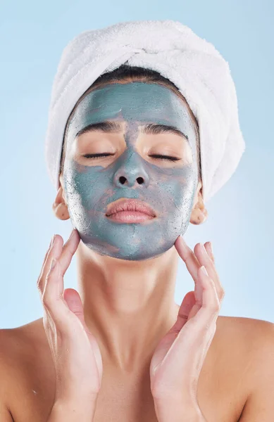 Skin, charcoal face mask and woman with morning self care routine, facial cleaning product and towel for hygiene skincare. Model with bathroom skin care beauty health on blue studio background mockup.