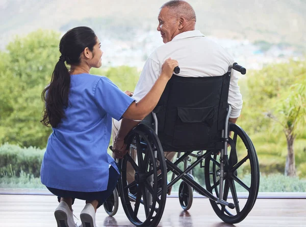 Healthcare, disability and man in wheelchair with nurse on retirement or nursing home patio. Senior care, happy disabled grandpa and woman caregiver with smile enjoying the view at hospital or clinic.