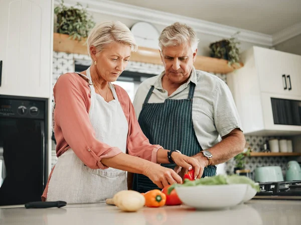 Elderly, couple and kitchen for cooking with vegetables for dinner with nutrition food. Man, woman and in retirement learning to cook for healthy diet in home together, love and vegan meal in house.
