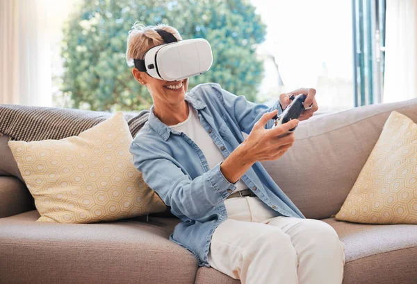 3d, virtual reality and play digital game online with controller and in a futuristic metaverse on sofa in her home. Vr headset, cyberspace and senior woman video gaming and streaming with tech.