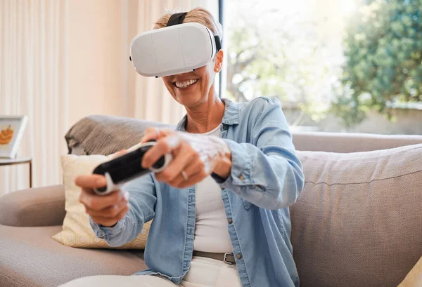 An elderly woman, virtual reality gaming and in retirement playing 3d online game in the living room of house. Senior grandmother in metaverse, vr technology and racing esports on sofa from her home.