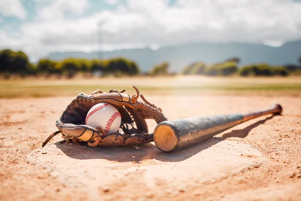 Baseball, sport and empty with a bat, ball and mitt on a base plate on a pitch outdoor after a competitive game. Fitness, sports and still life with exercise equipment on the ground for training.