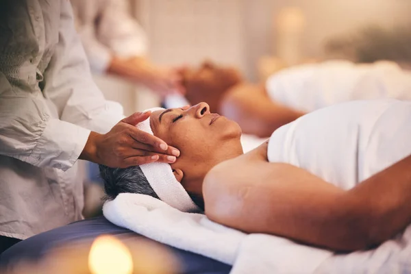 Spa, massage and head of senior woman while on table to relax for calm, peace and zen time with a therapist for health and wellness. Patient get facial with cosmetics, skincare and detox treatment.