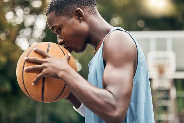 Sports, fitness and man with a kiss to a basketball in training, workout and athletic exercise outdoors. Culture, wellness and young player or athlete with passion and love for playing on court.