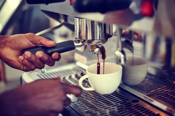 The perfect brew. Closeup shot of a male barista using an espresso machine to make a cup of coffee