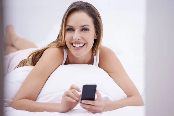 早上发短信一个年轻貌美的女人在床上看短信 — 图库照片