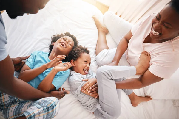 Tickle, laugh and relax with black family in bedroom for bonding, playful and affectionate. Funny, happiness and crazy with parents playing with children at home for wake up, morning and silly.
