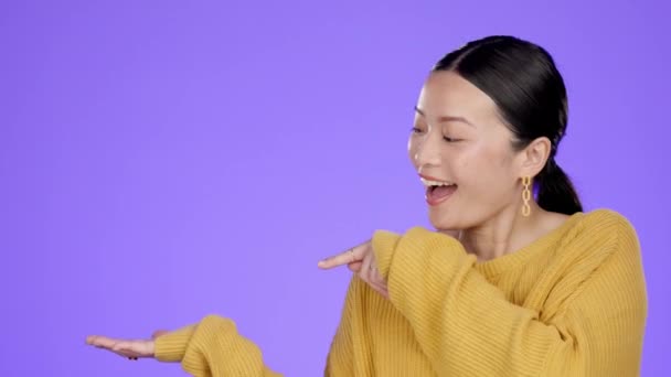 带着模特和产品摆放的女人 在紫色背景上被隔离的公告 打折销售 营销推广和广告复制空间 快乐的亚洲人在工作室指点 — 图库视频影像