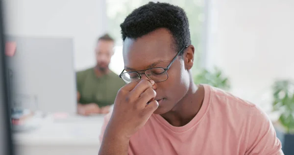 Stress, anxiety and mental health with a business black man removing his glasses while suffering from a headache at work. Burnout, frustration and migraine with a male employee working in his office.