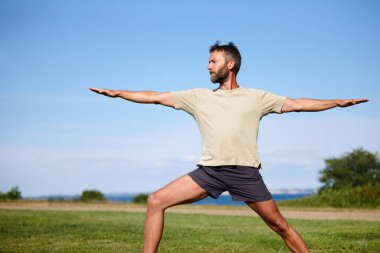 If it doesnt challenge you, it doesnt change you. a handsome mature man doing yoga outdoors clipart
