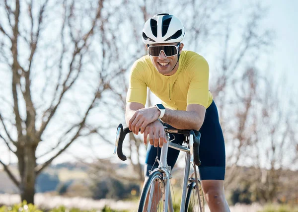 Cycling, fitness and man with bike in park, smile and take break from cyclist outdoor with helmet for safety. Sunglasses, happy male and athlete, training for race and exercise in nature with bicycle.
